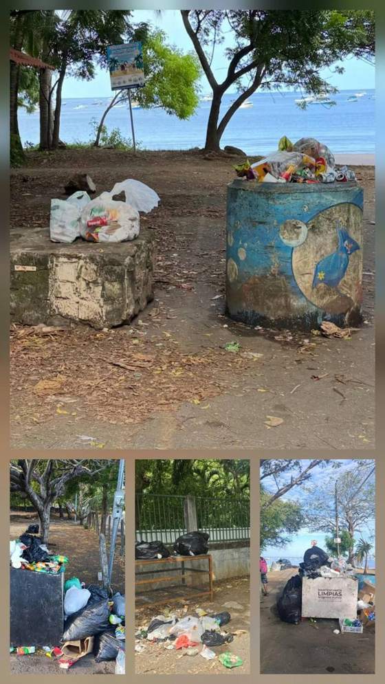 Overflowing bins and litter at a beach entrance.